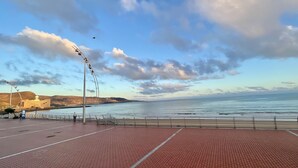 A paved walkway with a view of the sea and a distant building. - Las Canteras View Home (Las Palmas de Gran Canaria)