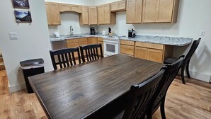 Een moderne keuken met houten kasten, een granieten aanrechtblad en een eethoek met een houten tafel en stoelen.