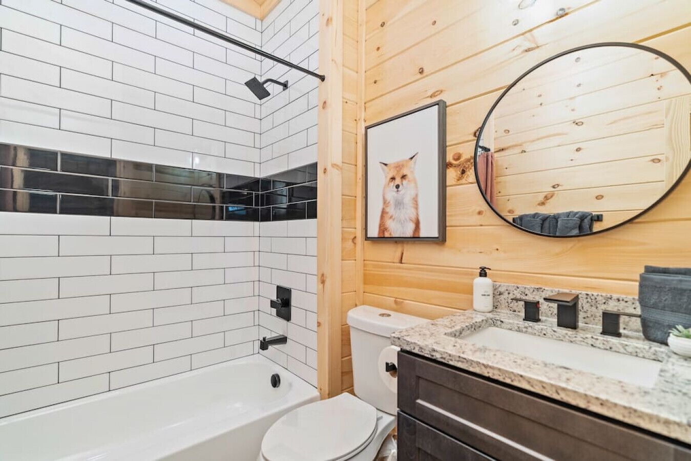 A modern bathroom with a white tiled shower, a toilet, and a sink with a granite countertop.
