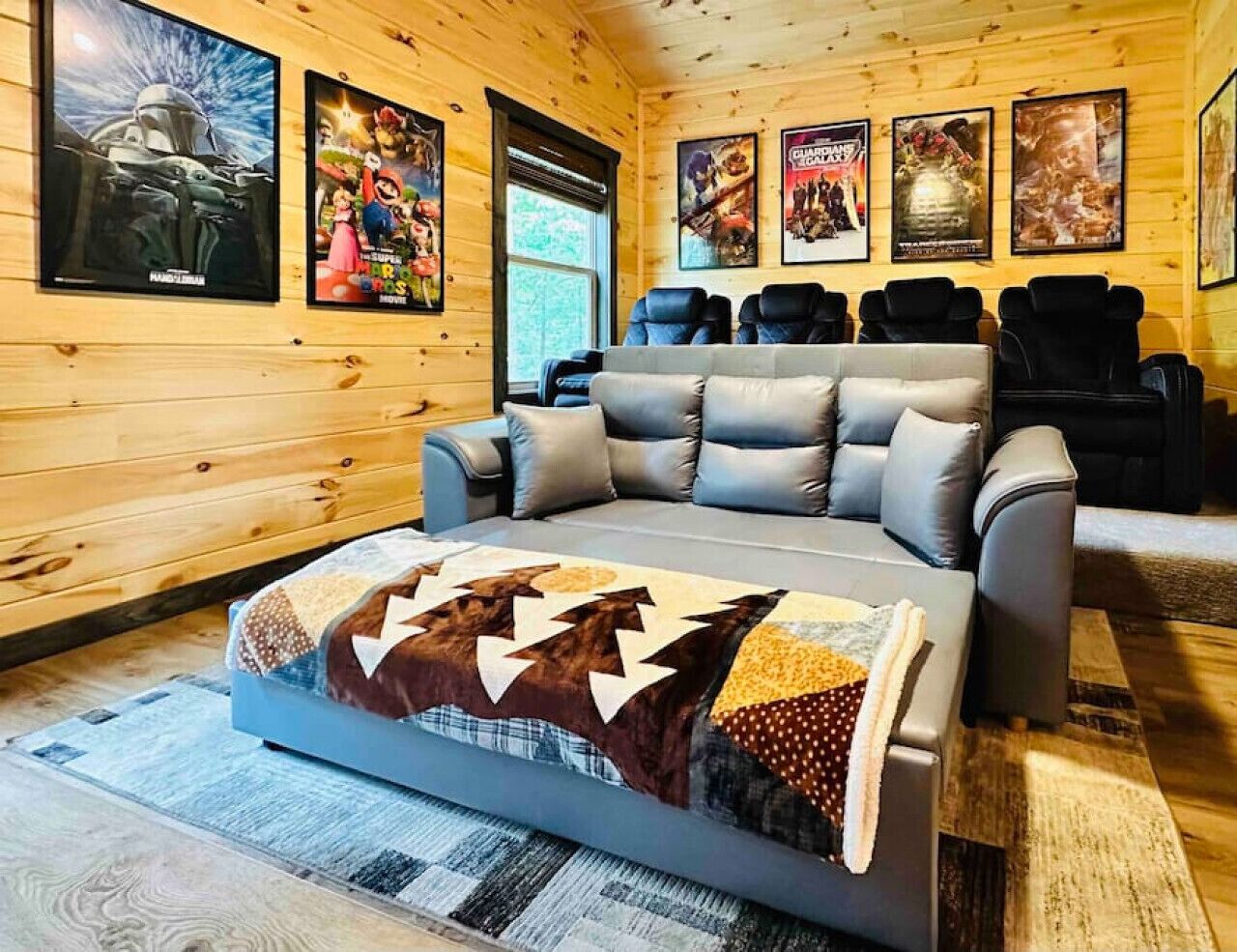 Une pièce chaleureuse avec un grand canapé, un plaid à motifs et des affiches de films accrochées au mur.