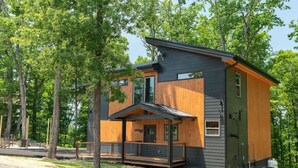 A modern two-story house with a wooden deck and a large window.