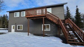 A two-story building with a wooden deck and a staircase. - Alaska Summers Lodge Loft-Near Mouth of Kasilof River (Cohoe)