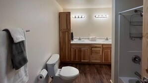 A compact bathroom with a toilet, sink, and wooden cabinets. - Alaska Summers Lodge Loft-Near Mouth of Kasilof River (Cohoe)