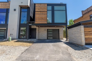 A modern two-story building with a mix of wooden and glass facades, numbered 224E, featuring a driveway and a gravel area. - 224 Frisco Alley Unit E By Summit County Mountain Retreats (Frisco)