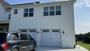 A two-story white house with a garage, a parked SUV, and a clear blue sky. - Spacious loft style apartment with gorgeous view (Watertown)