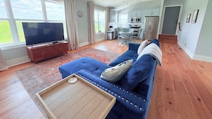 A spacious living room with a blue sofa, wooden coffee table, and a TV. - Spacious loft style apartment with gorgeous view (Watertown)