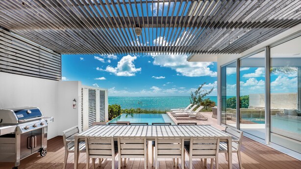 A modern outdoor patio with a pool, a grill, and a view of the ocean. - Beachfront Villa w/ Private Pool & Concierge – Villa Helios (Long Bay Beach)