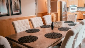 A dining table with a wooden surface, surrounded by white upholstered chairs.
