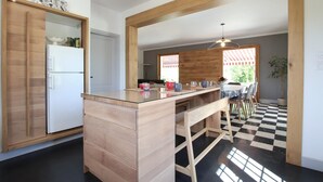 A modern kitchen with wooden cabinetry, a central island, and a checkered floor. - Arlotia - Ascarat - Gîte (ASCARAT)