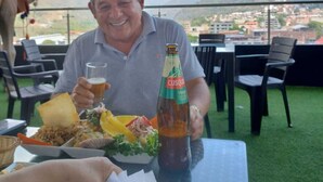 A man seated at an outdoor table with a bottle of Cusqueña beer and a glass of beer, with a scenic mountain view in the background. - HOTEL BURJ KHALIFA (Santa Ana)