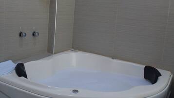 A modern bathroom with a freestanding bathtub, a showerhead, and two faucets.