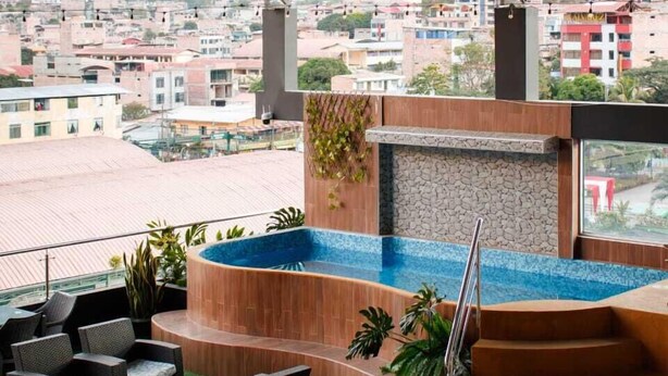 A rooftop terrace with a pool, outdoor seating, and a view of the cityscape. - HOTEL BURJ KHALIFA (Santa Ana)