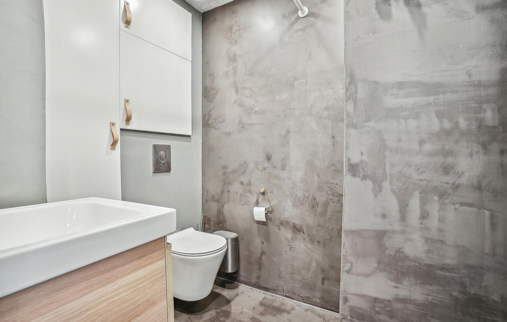 Ein Badezimmer mit einer weißen Badewanne, einer Toilette und einer Duschkabine mit einer strukturierten Wand.