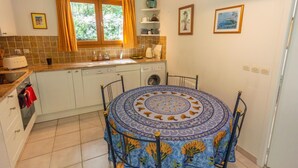A compact kitchen with a dining table, a washing machine, and a window with curtains. - "Azur Blue" Villa - Rural Peace with private pool (Peymeinade)