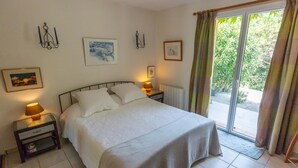 A bedroom with a bed, two bedside tables with lamps, a radiator, and a sliding glass door leading to a balcony. - "Azur Blue" Villa - Rural Peace with private pool (Peymeinade)