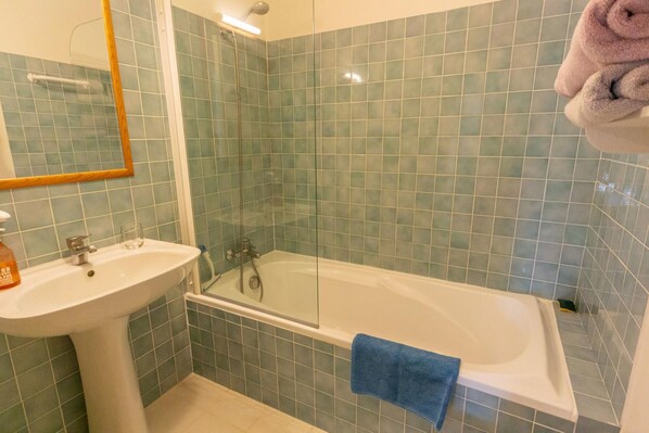Un baño con lavamanos, espejo y bañera.