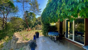 A patio with a table and chairs, surrounded by greenery and a stone wall. - "Azur Blue" Villa - Rural Peace with private pool (Peymeinade)