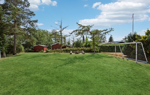 Ein gepflegter Garten mit einem Fußballtor, einer Bank und zwei roten Gartenhäusern.