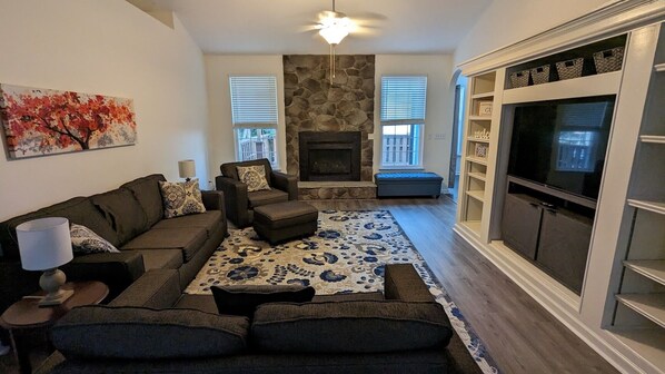 A living room with a sofa, chairs, a fireplace, a TV, and a stone wall.