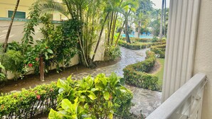 Ein üppiger Garten mit einem Wasserspiel, Palmen und einem Pool im Hintergrund.