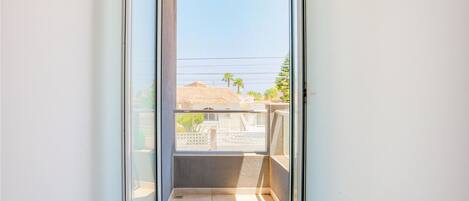 A balcony with a clear view of a residential area, including houses and palm trees.