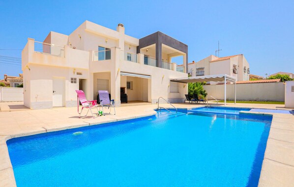Une maison moderne à deux étages, dotée d’une piscine, de plusieurs balcons et d’un patio couvert.