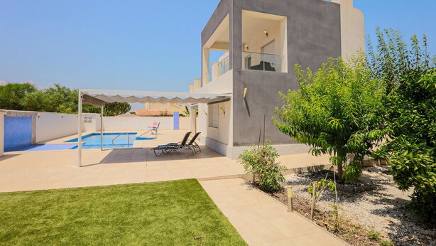 A modern two-story house with a swimming pool, a covered patio, and a well-maintained lawn.
