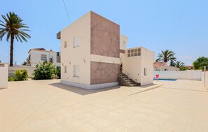 Un bâtiment moderne à deux étages, doté d’un toit plat, d’un escalier menant à l’étage supérieur et d’une petite structure adjacente.
