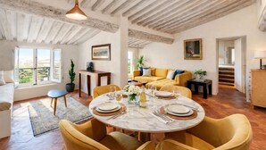 A dining area with a round table set for four, a sofa, and a staircase leading to another level.