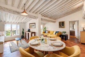 A dining area with a round table set for four, a sofa, and a staircase leading to another level.