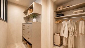A walk-in closet with open shelving, a dresser with drawers, and hanging robes.