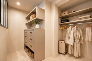 A walk-in closet with open shelving, a dresser with drawers, and hanging robes.