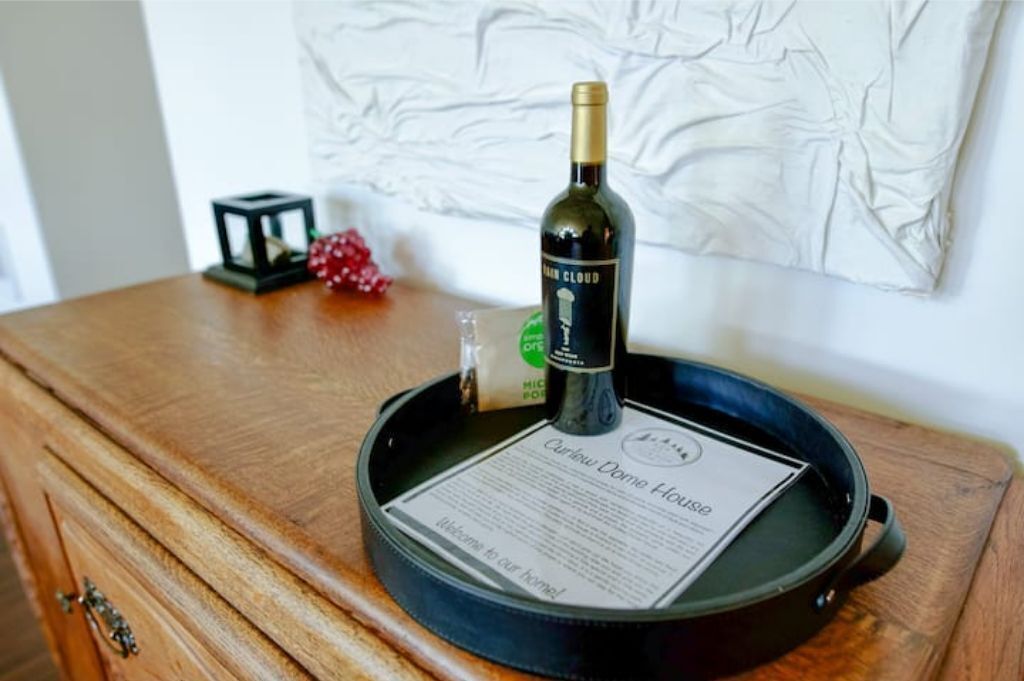 Una botella de vino sobre una bandeja, junto con un menú, en una mesa de madera.