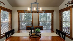 Une salle à manger avec une table en bois, des chaises et un lustre.