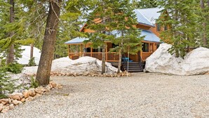 A log cabin with a metal roof, surrounded by large rocks and trees. - Gorgeous Unique, Rustic Cabin on Arapaho! 2 Kings, Loft Area with a Full, and a Bunk Room! (Duck Creek Village)
