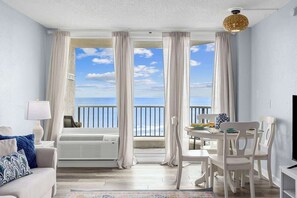 A room with a balcony, a dining table, chairs, a sofa, a TV, and a lamp. - Sunrise Shores Escape 1BR Unit (Myrtle Beach)