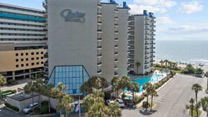 Un hotel amb piscina, palmeres i vista a l'oceà.