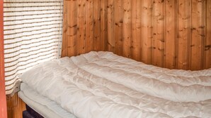 A single bed with a white duvet in a room with wooden panel walls. - Nice home in Rauland with kitchen (Rauland)