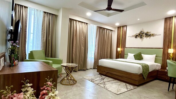 Una habitación de hotel moderna con una cama, un escritorio, una silla, una mesa redonda pequeña y un ventilador de techo.