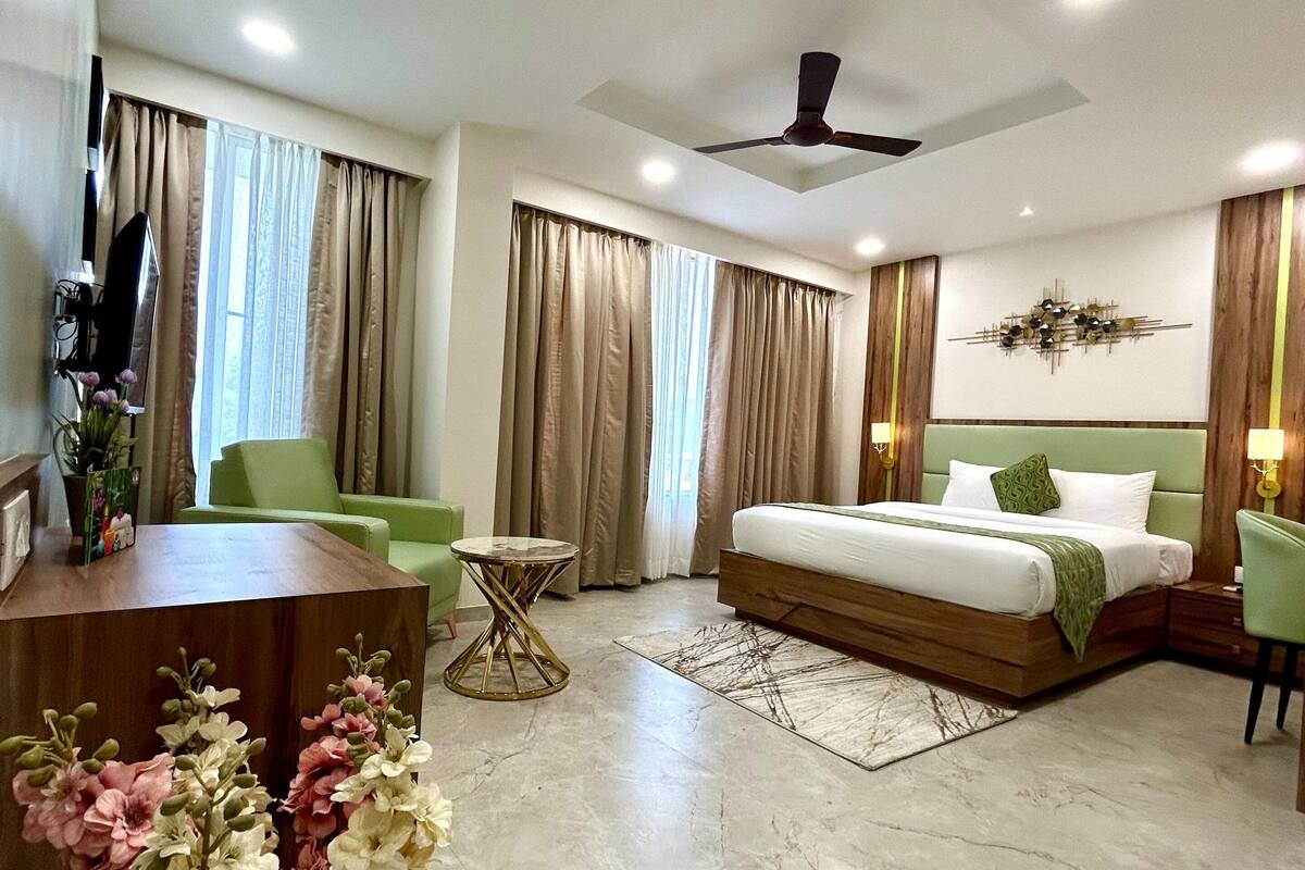 Una habitación de hotel moderna con una cama, un escritorio, una silla, una mesa redonda pequeña y un ventilador de techo.