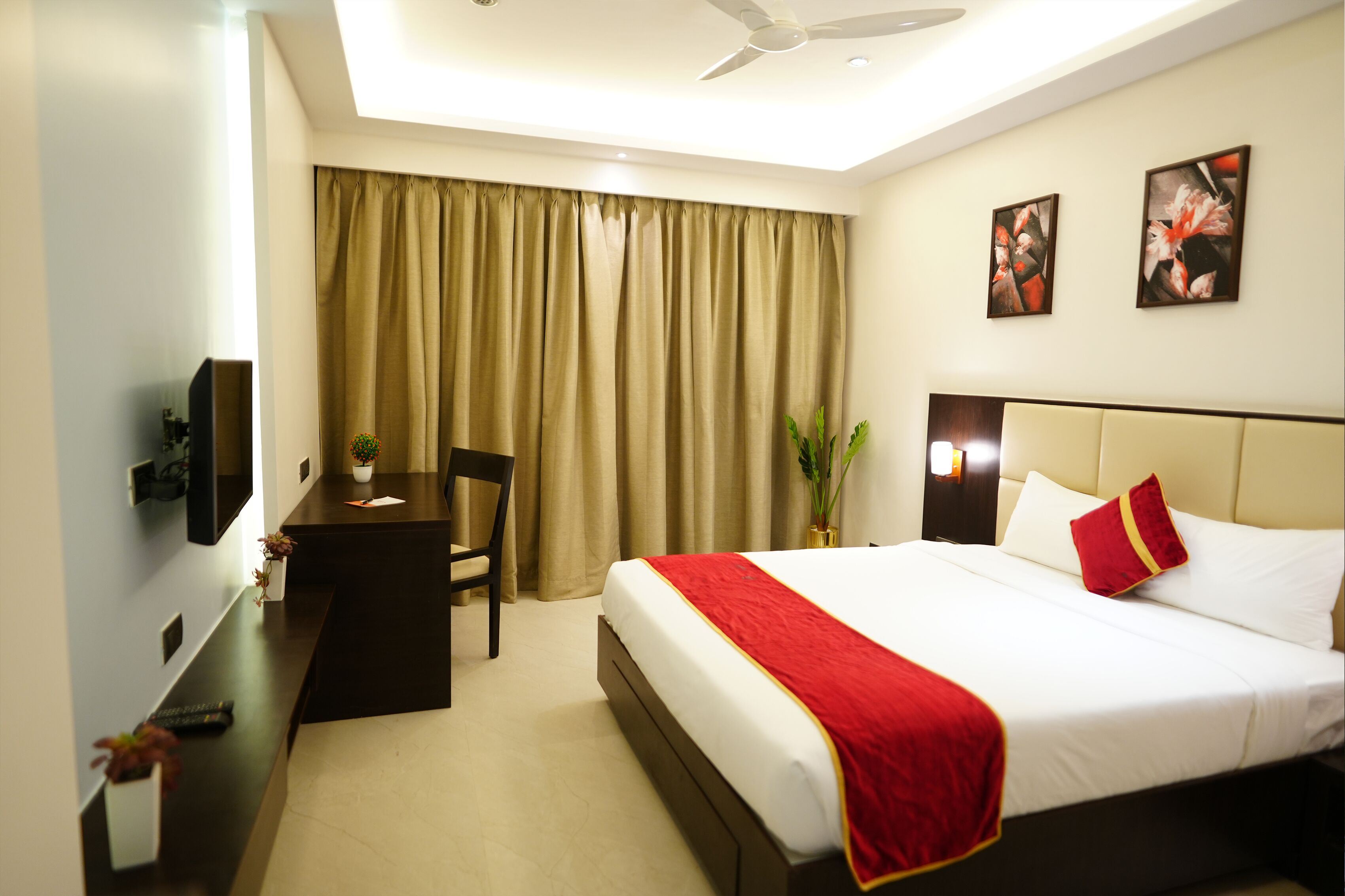 Une chambre d’hôtel équipée d’un lit, d’un bureau, d’une chaise, d’une télévision et d’un ventilateur de plafond.