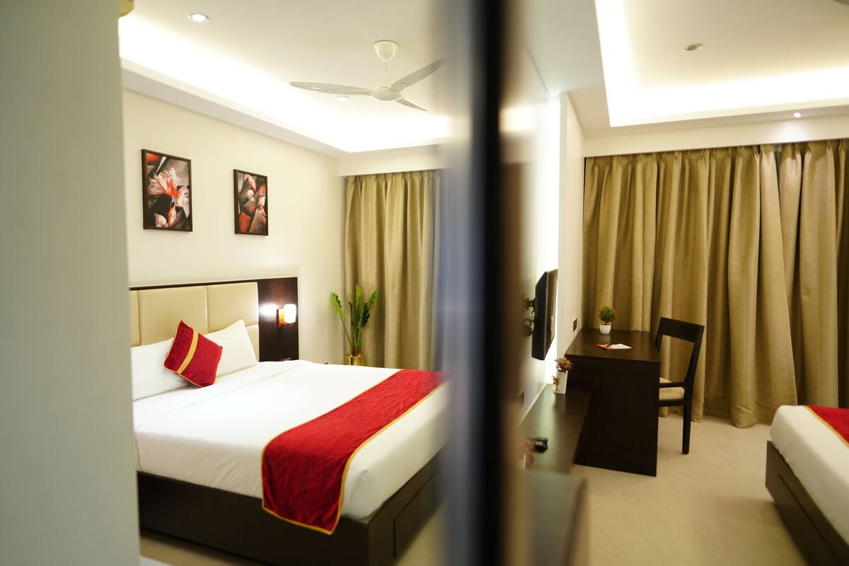 Una habitación de hotel con cama, escritorio, silla y televisión.