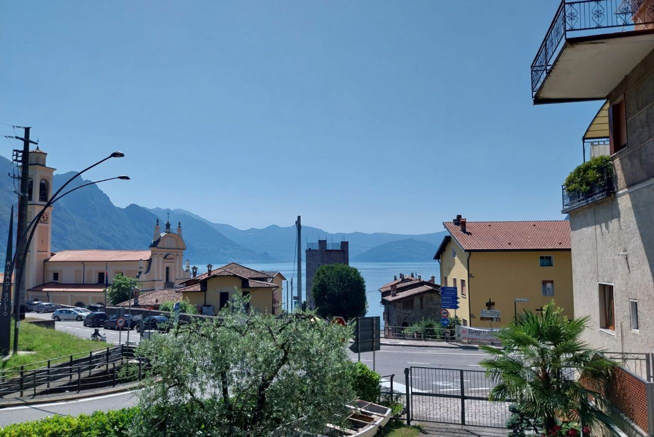 A coastal town with a prominent church, a tower, and a view of the sea and mountains.