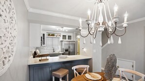 A modern kitchen with a central island, white cabinetry, and a chandelier.