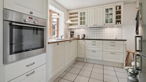 Una cocina con armarios blancos, un horno de acero inoxidable y piso de baldosas.