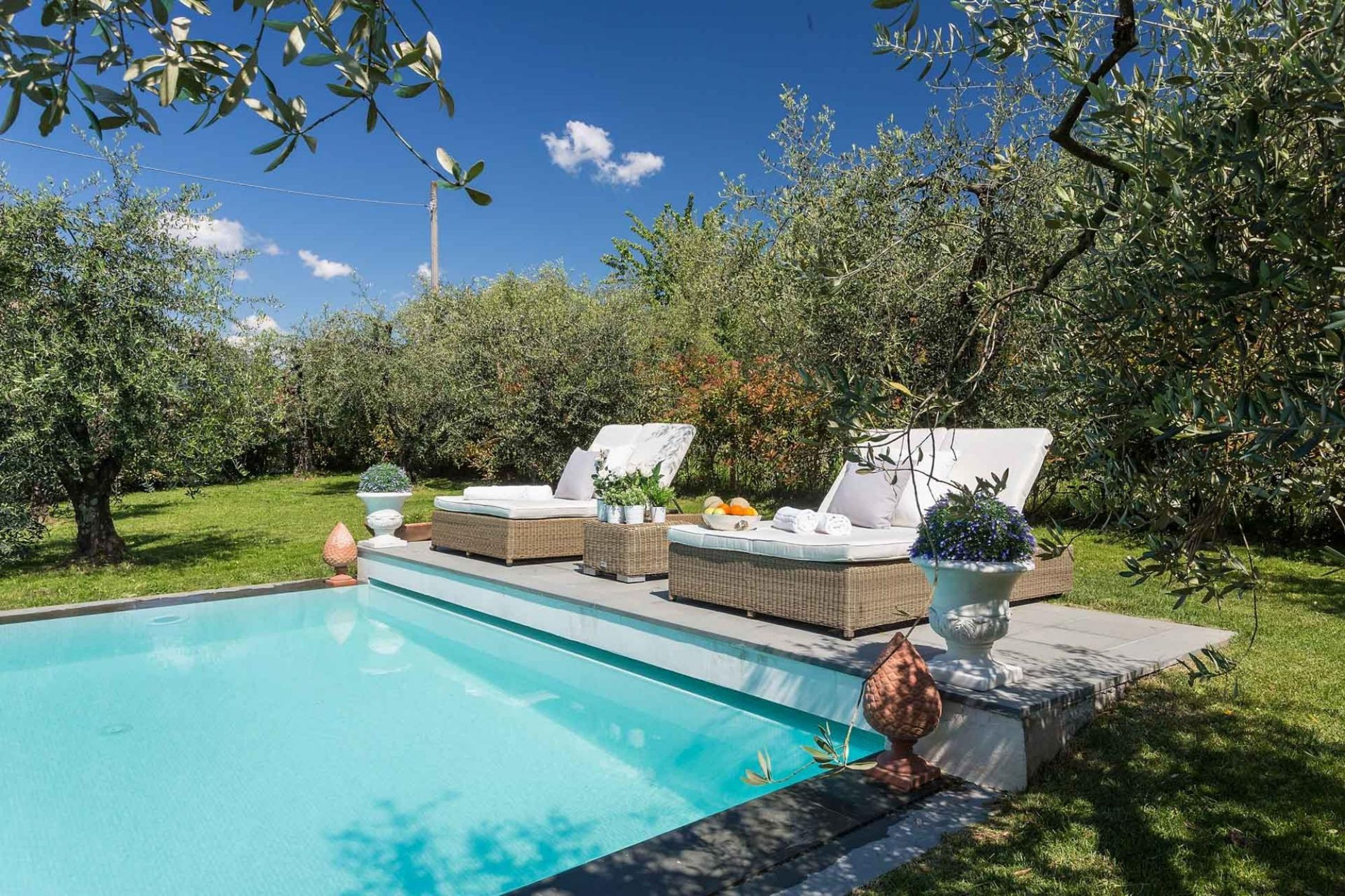A swimming pool with lounge chairs and potted plants.