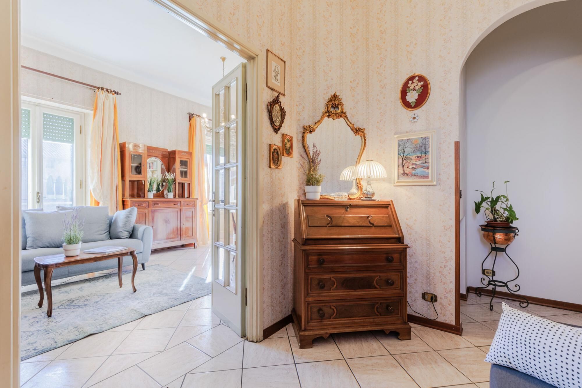 A living room with a sofa, a wooden cabinet, a lamp, and a potted plant.