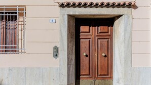 A building entrance with a double wooden door, a metal gate, and a concrete base. - La Casa in Centro in Lucca (Lucca)