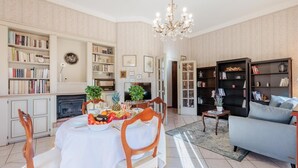 A spacious living room with a dining area, a chandelier, and bookshelves filled with books. - La Casa in Centro in Lucca (Lucca)