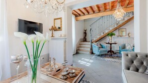 A spacious living room with a wooden coffee table, a chandelier, and a staircase leading to an upper level.